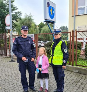 zdjęcie pamiątkowe przed wejściem do szkoły policjantów i dziewczynki