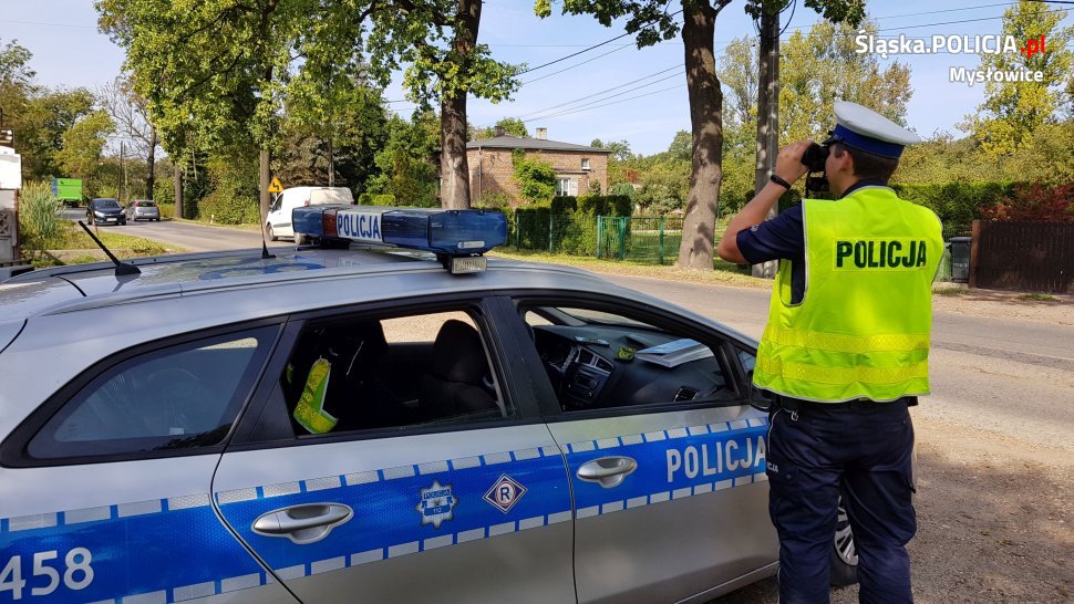 policjant obserwuje przez lornetkę ruch pojazdów