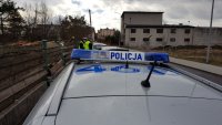 policyjny radiowóz i policjanci kontrolujący kierowcę