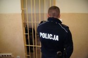 policjant zamykający kratę pomieszczenia dla zatrzymanych