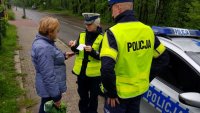 policjanci wręczają pieszej elementy odblaskowe