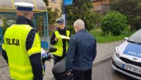 policjanci wręczają kamizelkę odblaskową kierującemu skuterem