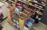 Zdjęcie z monitoringu, na którym dwóch mężczyzn dokonuje kradzieży alkoholu.