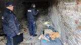 Dwóch policjantów kontrolujących pustostan zamieszkiwani przez osoby bezdomne