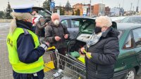 policjantka wręcza opaski odblaskowe seniorom podczas akcji Bezpieczny pieszy