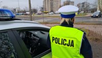 policjantka przy radiowozie obserwuje ruch pojazdów i pieszych