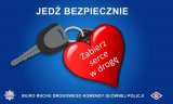 U góry biały napis jedź bezpiecznie. Poniżej kluczyk samochodowy przyczepiony do czerwonego serca a na nim napis: Zabierz serce w drogę.
Poniżej obrazka logo Policji i biały napis: Biuro Ruchu Drogowego Komendy Głównej Policji i logo Biura. Całość umieszczona na niebieskim tle.