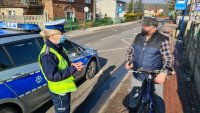 policjantka rozmawia z rowerzystami o ich bezpieczeństwie na drodze i wręcza elementy odblaskowe dla poprawy ich widoczności i bezpieczeństwa