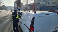 policjanci kontrolują kierowce białego samochodu dostawczego