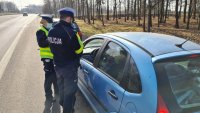 policjanci kontrolują kierowcę niebieskiego samochodu osobowego