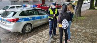 policjantka przeprowadza rozmowę z dwiema dziewczynkami nt. bezpieczeństwa podczas jazdy na hulajnodze elektrycznej