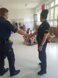 policjant i policjantka prezentują sposoby na uwolnienie się z chwytu za rękę