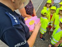 policjantka rozdaje dzieciom laurki w kształcie kwiatka