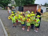 Zdjęcie grupowe przedszkolaków i policjantki trzymających w rękach przygotowane na Dzień Ojca laurki