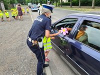 policjantka razem z dzieckiem wręcza kierowcy laurkę