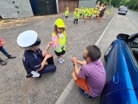policjantka i dziewczynka rozmawiają z kierowcą trzymając w ręce laurkę z napisem: Tata najlepszy kierowca świata!