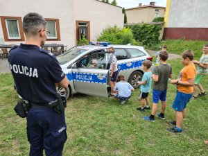 policjant obserwuje dzieci bawiące się przy radiowozie