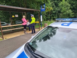 policjantka ruchu drogowego rozmawia z kobietą i mężczyzną na przystanku na autobusowym