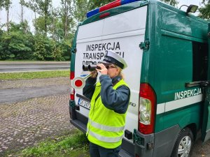 Funkcjonariuszka Inspekcji Transportu Drogowego obserwuje ruch pojazdów przez lornetkę