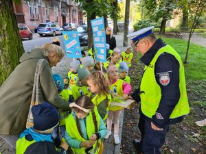 policjant ruchu drogowego wręcza przedszkolakom odblaski