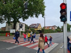 policjant przeprowadza pierwszoklasistów przez przejście dla pieszych