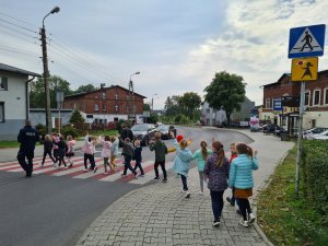 policjant przeprowadza pierwszoklasistów przez przejście dla pieszych