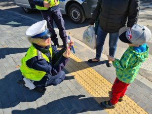 policjantka ruchu drogowego wręcza odblask chłopcu