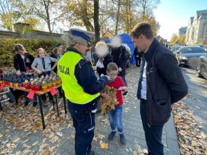 policjantka wręcza dziecku element odblaskowy