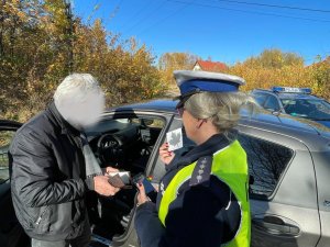 policjantka wręcza kierowcy naklejkę - listek