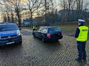 policjant i policjantka dokonują kontroli pojazdu