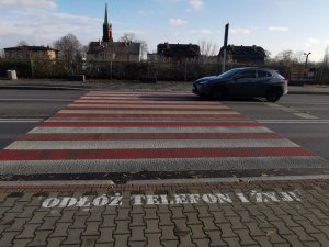 przejście dla pieszych, samochód i hasło&quot;odłóż telefon i żyj