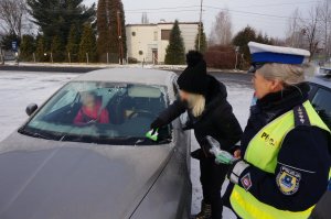 policjantka wręczająca kierującym skrobaczkę do szyb