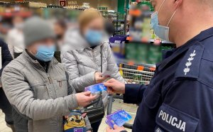 policjanci rozdający ulotki klientom przy stoisku z fajerwerkami