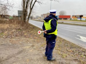 policjant stojący przy drodze z policyjnym &quot;lizakiem&quot; w ręce