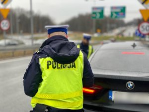 policjant podchodzący do czarnego pojazdu, zatrzymanego do kontroli