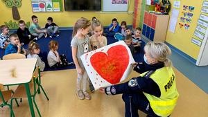 policjanci odbierający od dzieci serduszka dla seniorów