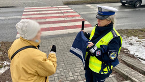 policjantka rozdająca elementy odblaskowe przechodniom