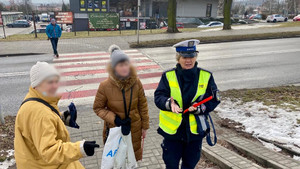 policjantka rozdająca elementy odblaskowe przechodniom