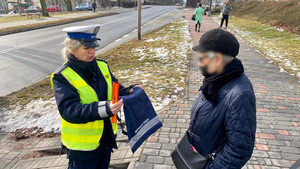 policjantka rozdająca elementy odblaskowe przechodniom