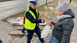 policjantka rozdająca elementy odblaskowe przechodniom