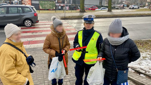 policjantka rozdająca elementy odblaskowe przechodniom