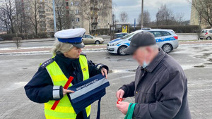 policjantka rozdająca elementy odblaskowe przechodniom