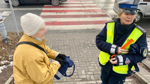 policjantka rozdająca elementy odblaskowe przechodniom