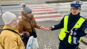 policjantka rozdająca elementy odblaskowe przechodniom