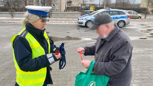 policjantka rozdająca elementy odblaskowe przechodniom