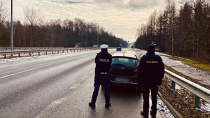 policjant oraz strażnik miejski obserwujący przejście dla pieszych