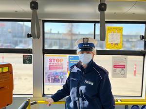 policjantka naklejająca plakaty w autobusie i na przystanku