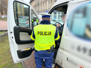 policjant w trakcie kontroli drogowej stojący przy samochodzie