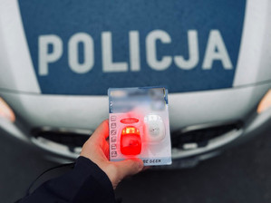 rowerowe światełka led, w tle maska radiowozu z napisem Policja