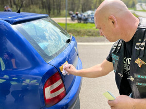 motocyklista naklejający na pojazd naklejkę